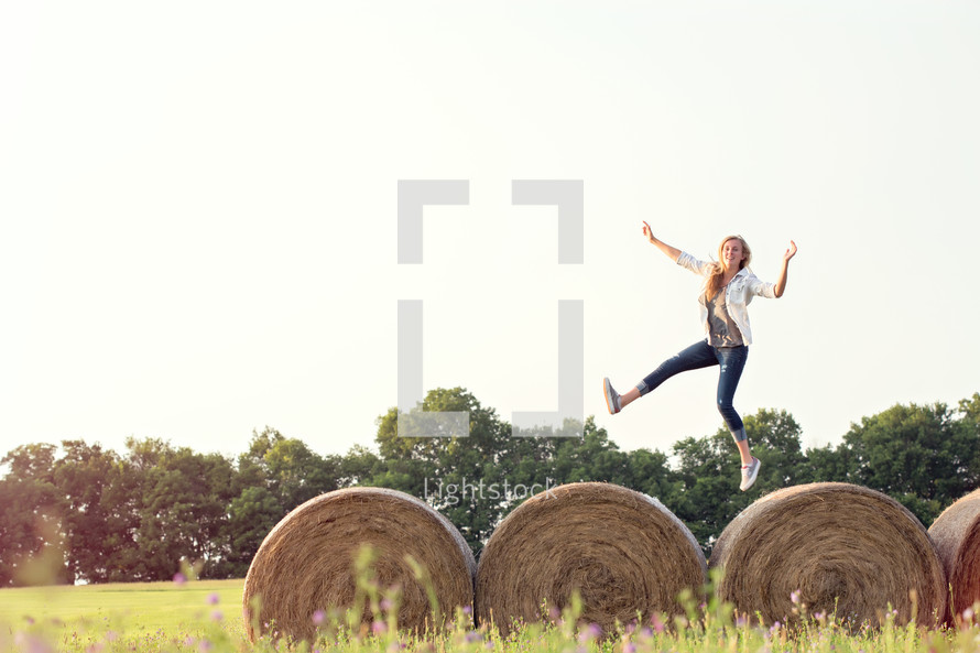 woman running and jumping on hay bales 