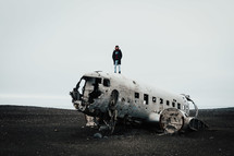 a man standing on the ruins of an airplane crash site 