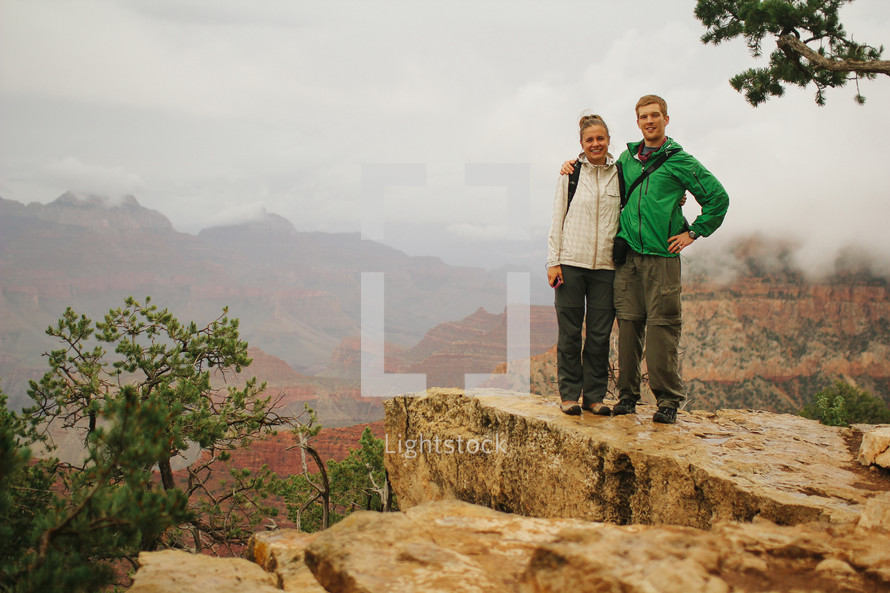couple posing in front of fog over a cliff 