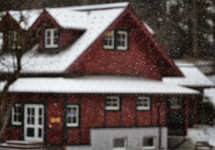 snow falling on a red house 