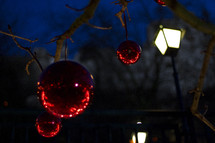 red Christmas ornaments hanging from a tree outdoors 