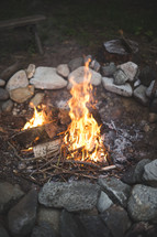 A campfire in a fire pit surrounded by rocks.