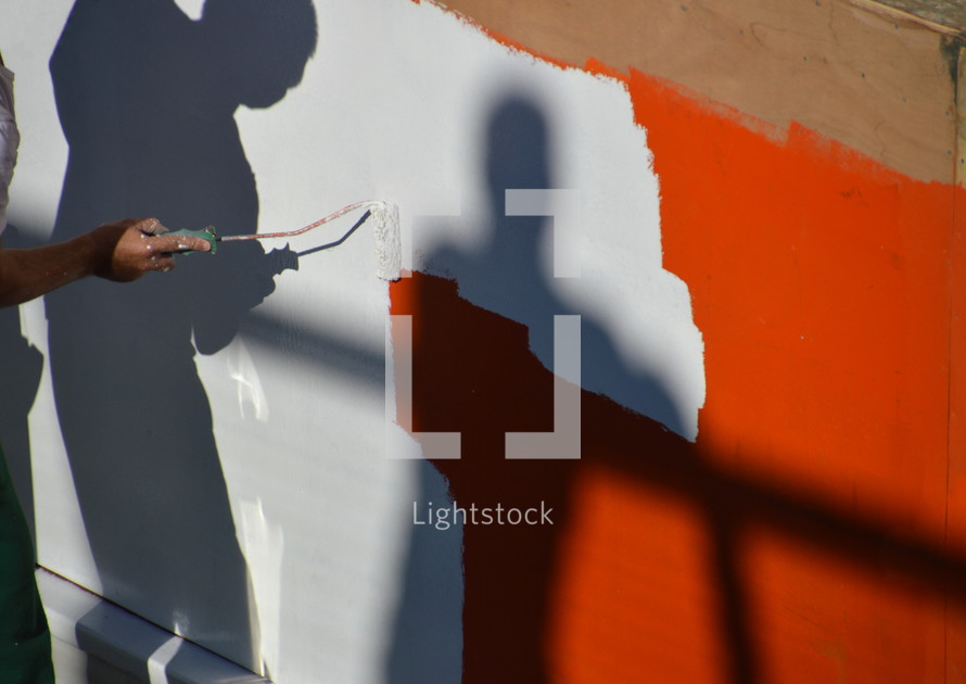 man painting over a red wall 