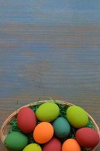 Easter eggs in a basket on blue wood background 