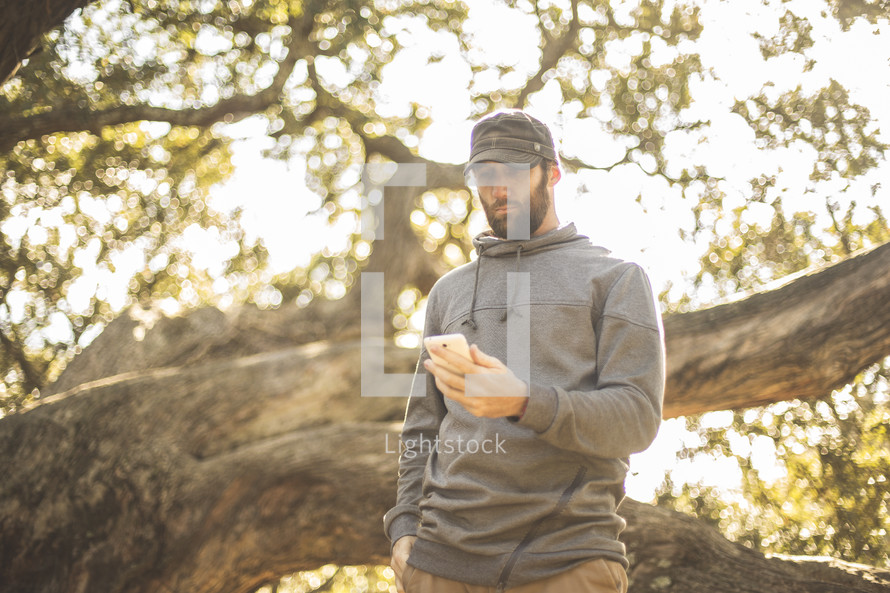 a man looking at his cellphone screen standing outdoors 