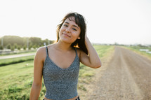 a young woman standing on a rural dirt road 