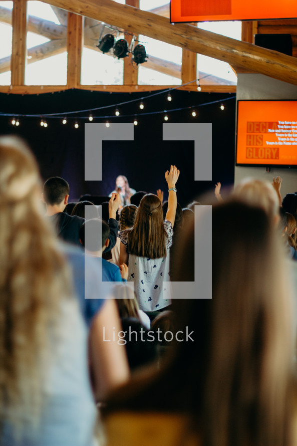 girl with arm raised during a worship service 