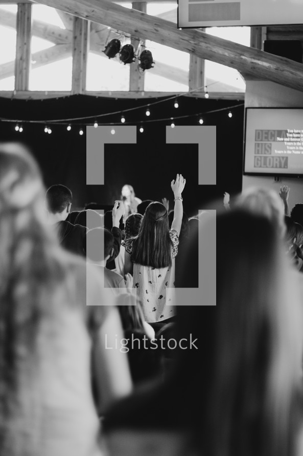 girl with arm raised during a worship service 