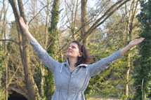 Woman with raised arms in adoration outdoors in nature.