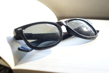 folded reading glasses on the pages of a Bible 