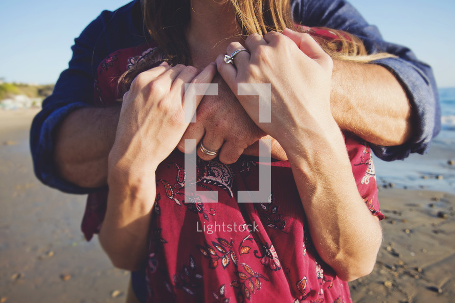husband and wife embracing on a beach 