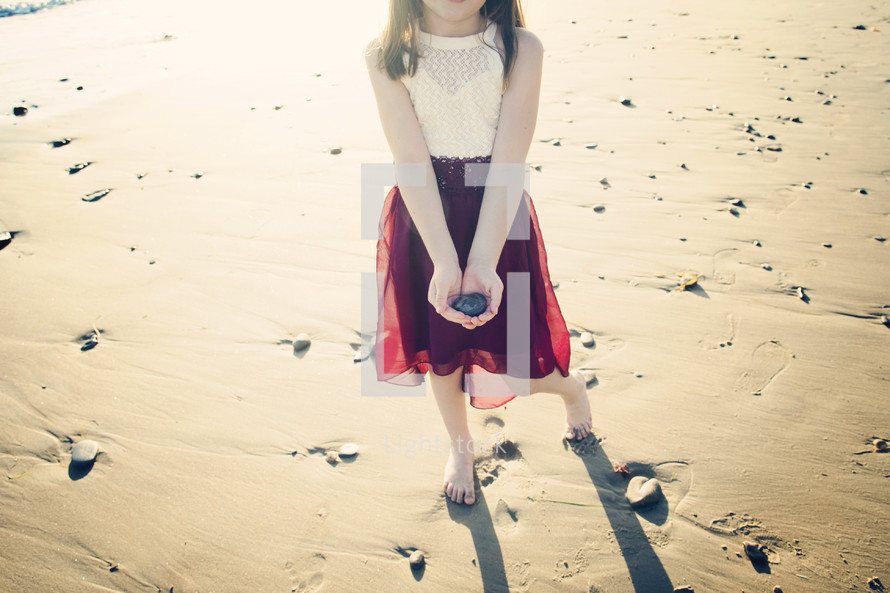 girl holding a rock on a beach 