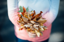 child holding fall leaves 