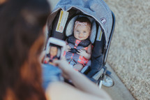 a mother taking a picture of her baby daughter in a stroller 