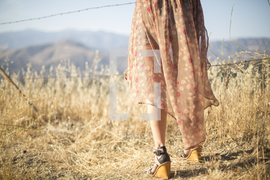 legs of a woman standing next to a barbed wire fence 