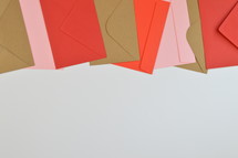 red, pink and brown envelopes in a row on white background with copy space  