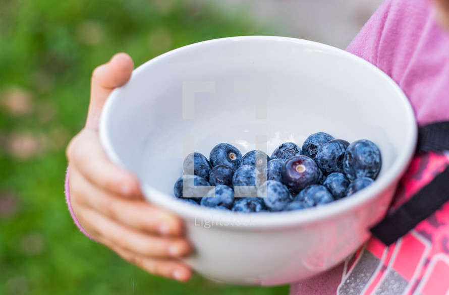 a girl holding blueberries 