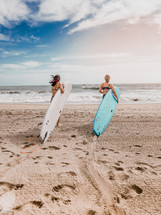 two women on the beach with surfboards 