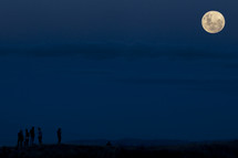 silhouettes under a full moon 