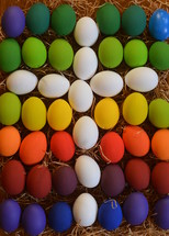 White cross between colorfully painted Easter eggs.
