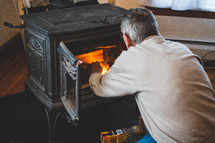 a man start a fire in a wood furnace stove 