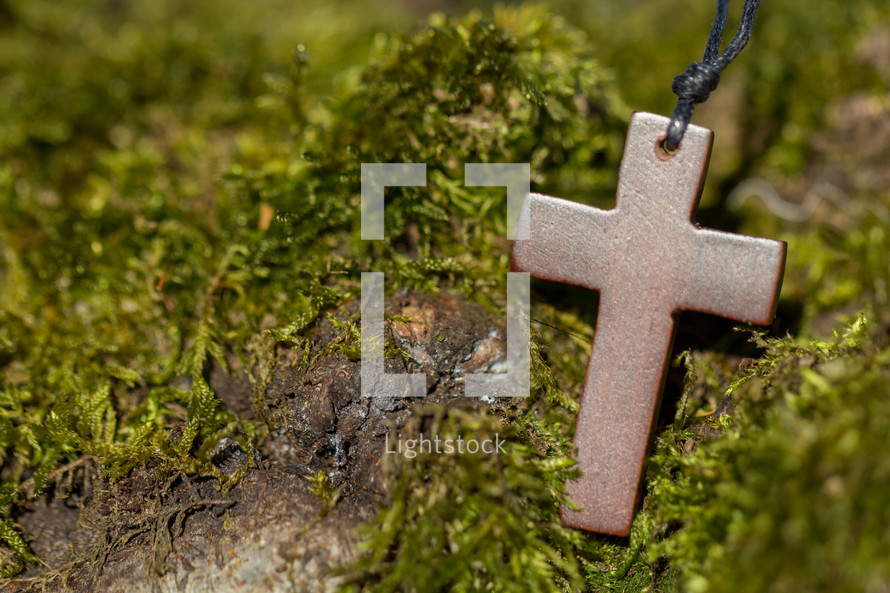 wooden cross necklace on moss 