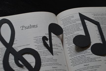 The Bible open to Psalms with musical notes covering it.
