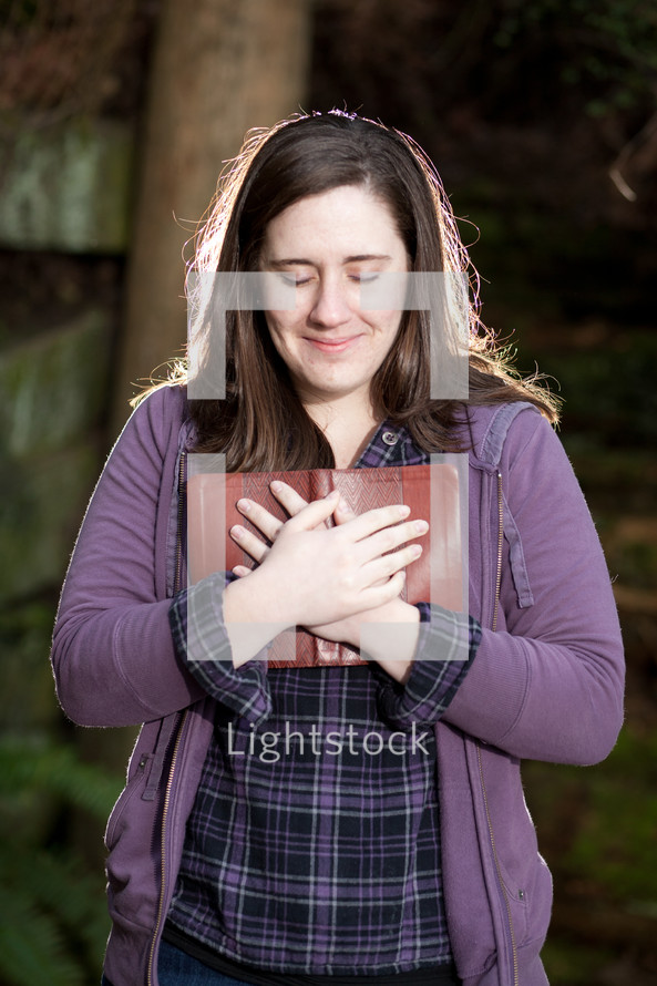 woman holding a Bible to her heart