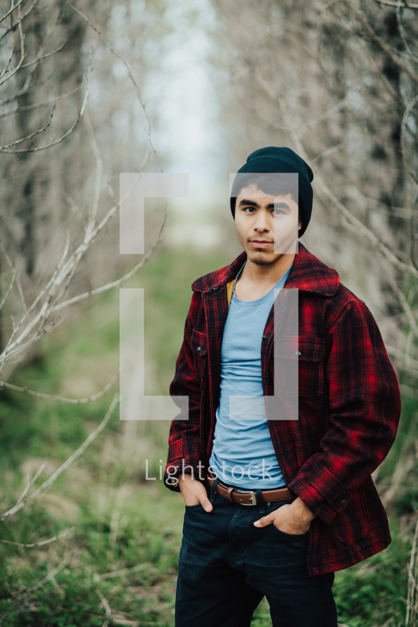 a man in a flannel shirt standing in a forest 