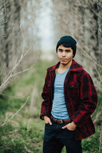 a man in a flannel shirt standing in a forest 