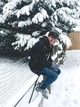 a man sitting on a fence in the snow 
