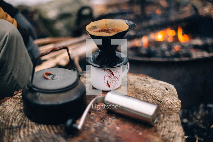 coffee grinder and slow brew coffee by a fire