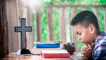 a boy reading a Bible outdoors and praying 