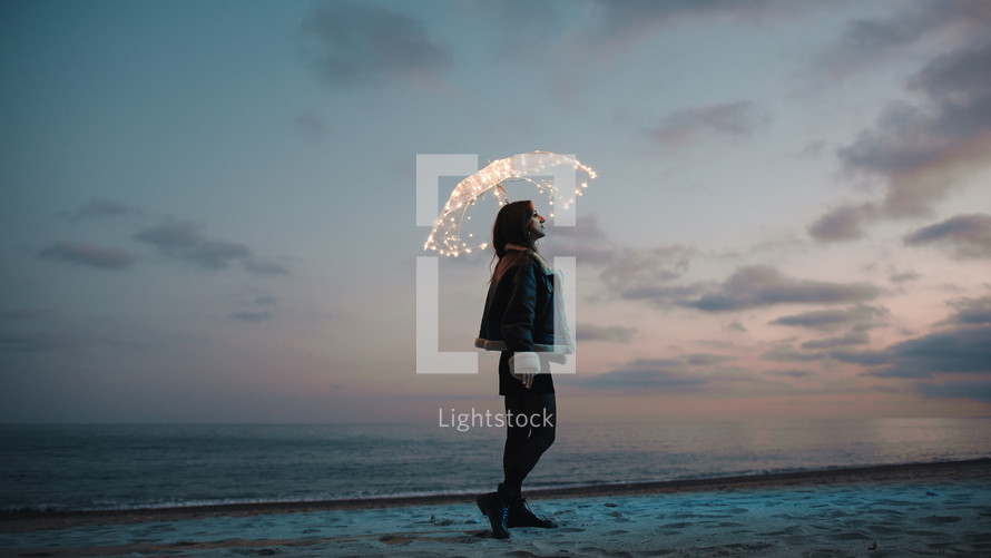 Glowing umbrella of a girl walking on the beach in the night outdoor