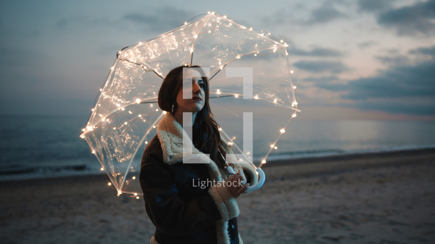 Glowing umbrella of a girl walking on the beach in the night outdoor