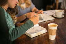 young women at a Bible study reading Bibles and drinking coffee 