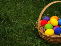 Basket of colored Easter eggs in the grass.
