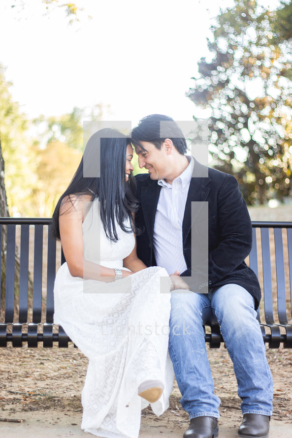 portrait of a bride and groom sitting on a bench outdoors 