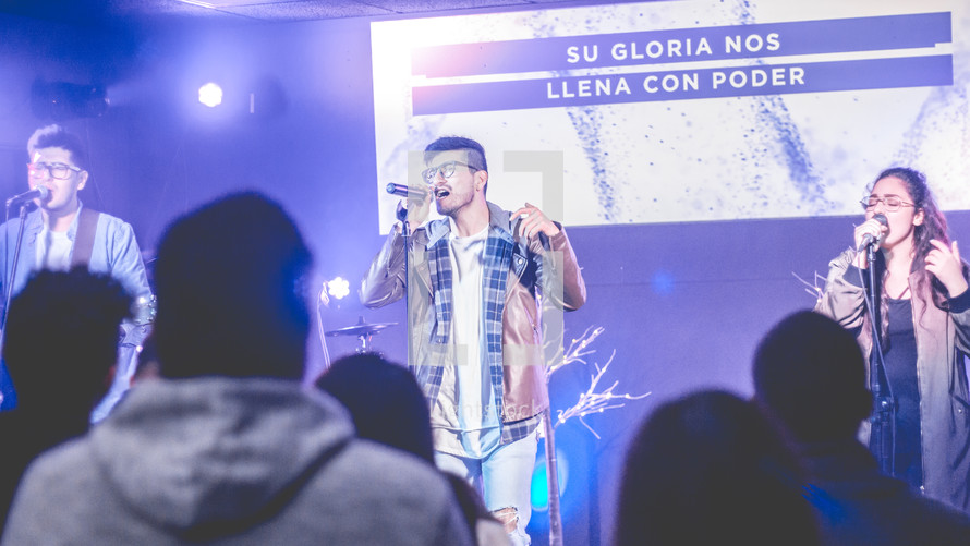people holding a microphone and singing during a worship service 