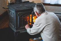 a man start a fire in a wood furnace stove 