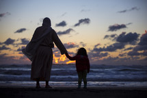 Jesus standing on a beach holding hands with a little girl 