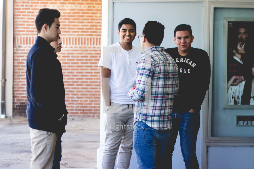young men gathered talking outdoors 
