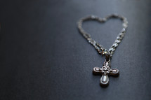 A metal bracelet shaped as a heart, with a cross pendant