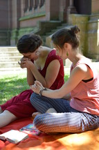 friends praying together sitting outdoors on a blanket next to a cathedral