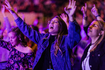 Young women with their hands raised in praise and worship.