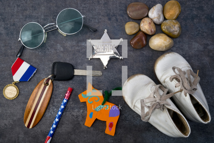 trinkets, medal, sheriff badge, car keys, baby shoes, stones, sunglasses, pencil 