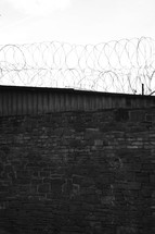 Brick wall with a barbed wire fence.
