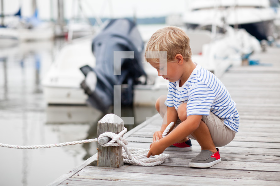 Boy holding a rope on a pier.