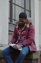 a man in a coat reading a Bible 