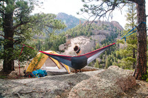 a woman camping sitting in a hammock 